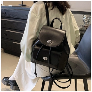 Detail of a chic black leather backpack with silver metal turn-lock and drawstring closure