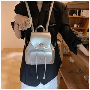 Detail of metallic silver mini backpack showing twist-lock closure and leather texture