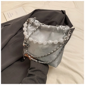 Detail of silver drawstring bucket bag with marble bead handle and metal skull charm