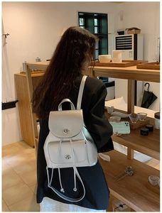 Detailed view of a silver metallic backpack with round twist locks shown on a model