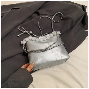 Detail of silver bucket bag with marble texture and white beaded handle on suit fabric