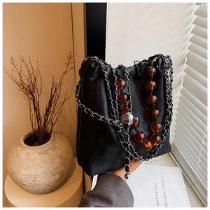 Detail of black jacquard bucket bag with amber beads and silver metal chain strap