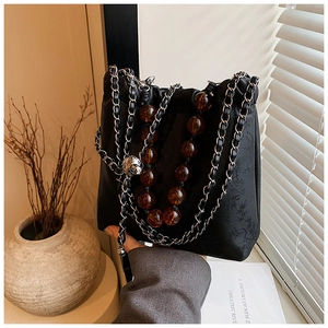 Detail of black drawstring bucket bag with bamboo pattern and amber beaded chain strap