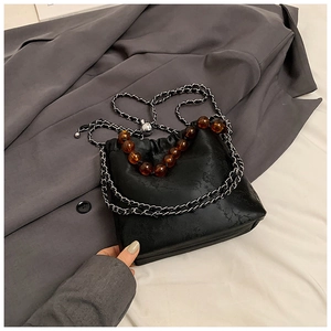 Detail of floral texture bucket bag with amber bead handle and metal chain strap