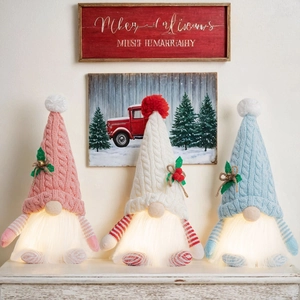 Close-up of glowing Christmas gnomes with warm LED lights and knitted hats detail