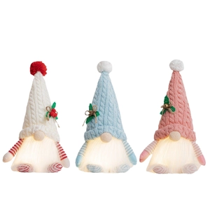 Three glowing Christmas gnomes with knitted hats in cream, blue, and pink colors