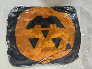 Detalle de funda de cojín cuadrada de lentejuelas con diseño de doble G en naranja y negro