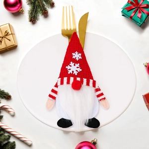 Porte-couverts de Noël gnome avec bonnet tricoté et couverts dorés posés sur une assiette