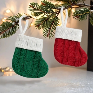 Close-up of red and green knitted Christmas mini stockings hanging on a festive pine branch