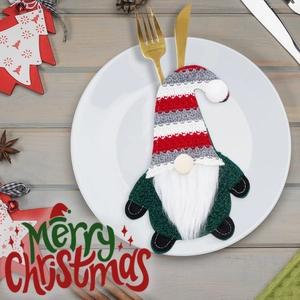Detalle de un portacubiertos de gnomo verde con gorro a rayas en un plato blanco