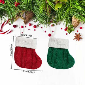 Detail of red and green knitted Christmas stockings with dimensions and festive pine decor