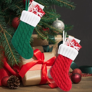 Detail von rot und grün gestrickten Mini-Weihnachtssocken an Baum und Geschenkbox
