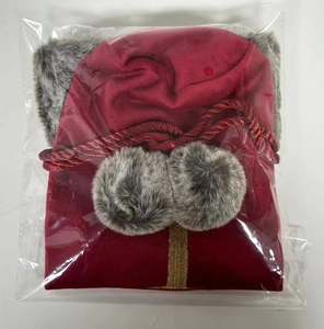 Detail of red velvet Christmas wine bottle cover with faux fur trim and pom-poms in package