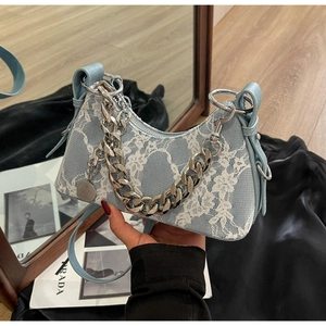 Close-up of light blue lace underarm bag with silver chain and white floral detail