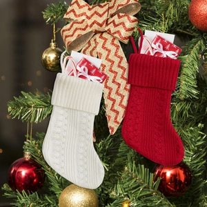 Gebreide kerstkousen in rood en gebroken wit aan een feestelijke kerstboom