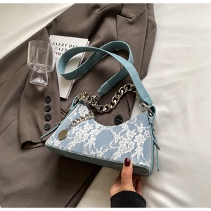 Detail of light blue lace underarm bag with silver chain and wide strap