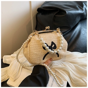 Détail d'un sac en paille style docteur avec nœud noir et bandoulière en perles
