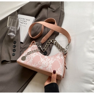 Close-up of pink underarm bag with white lace floral overlay and silver chain detail