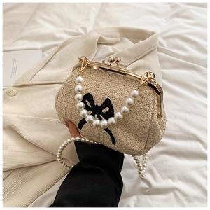 Détail du sac en paille tressée avec nœud noir et bandoulière en perles de luxe