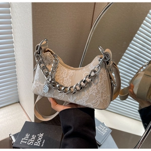 Detail of floral lace fabric with silver chain strap and metal logo on beige armpit bag