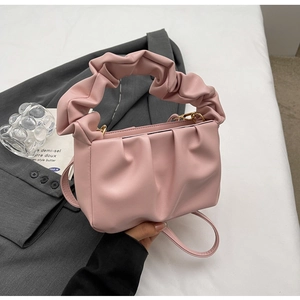Close-up of pink pleated cloud bag with scrunchie handle and detachable shoulder strap