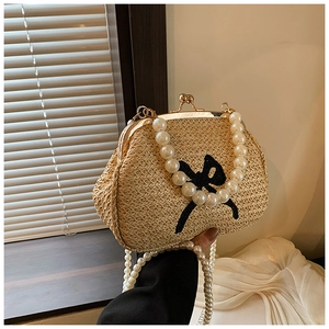 Détail du sac en paille avec nœud noir brodé et élégante bandoulière en perles