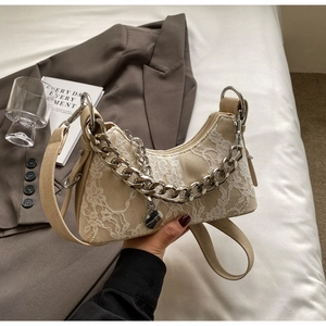 Detailed view of white lace overlay and chunky silver chain on khaki underarm bag