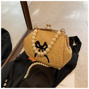 Détail du sac en paille tressée avec poignée en perles et broderie de nœud