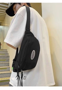 Détail du sac bandoulière noir montrant le tissu imperméable et les fermetures éclair