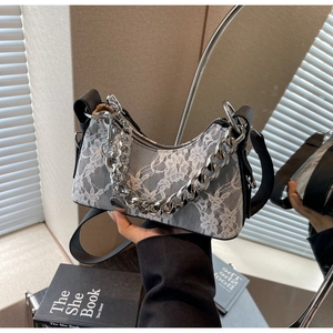 Close-up of floral lace texture and silver metal chain on retro underarm bag