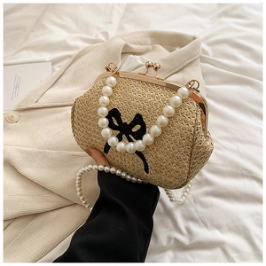 Détail du sac en paille avec nœud noir, poignée en perles et fermoir doré vintage