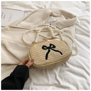 Détail du sac en paille avec broderie nœud noir, anse en perles et fermoir métallique