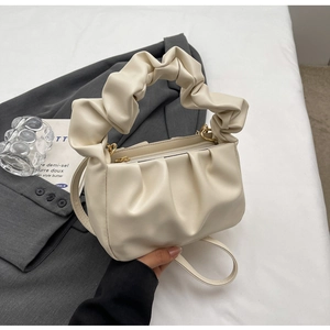 Detailed close-up of cream pleated cloud bag showing soft PU texture on gray blazer