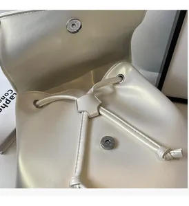 Détail du sac à dos blanc nacré avec boucle magnétique argentée et fermeture à cordon