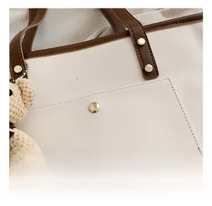 Detail der Kontrast-Tote-Bag mit goldenen Beschlägen und Strickbär-Anhänger mit Perlen