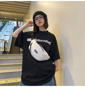 Gros plan d'un sac bandoulière de sport blanc avec badge noir porté par un mannequin
