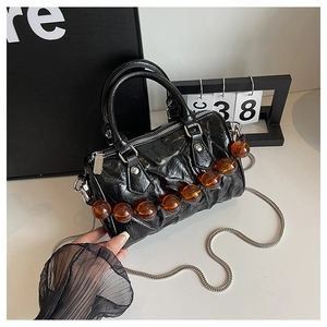 Detalle del bolso Boston negro plisado con cuentas de ámbar y cadena plateada
