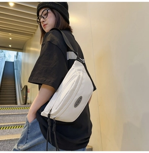Détail du sac bandoulière en nylon blanc avec écusson 16'07'G et étiquette de logo