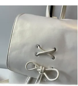 Détail d'un sac à dos blanc en cuir PU avec laçage croisé et nœud décoratif
