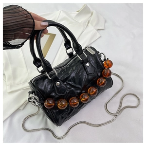 Detalle del bolso Boston negro plisado con cuentas de ámbar y correa de cadena plateada