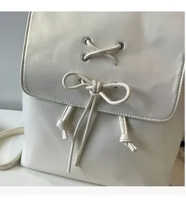 Vue détaillée du sac à dos blanc style ballet avec nœuds papillon et laçage chic