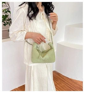 Detail view of mint green crescent bag with clear acrylic handle and metal chain strap