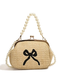 Sac à main en paille avec bandoulières en perles et nœud noir sur fond blanc