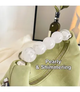 Macro shot of sage green suede bag featuring pearlescent bead handle and silver zipper detail
