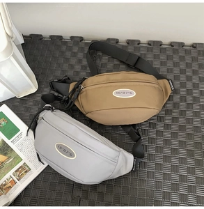 Détail de sacs banane en nylon beige et gris avec des sangles réglables sur tapis gris