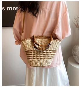 Detail of hand-woven straw bucket bag featuring bamboo handles and leather strap