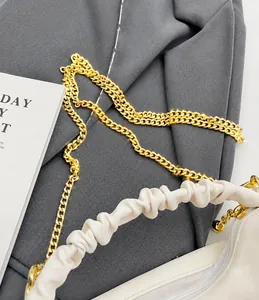 Detail of ivory pleated handle bag featuring a chunky gold chain strap on soft leather