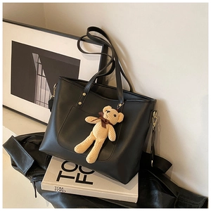 Detail der schwarzen Leder-Shopper mit beigem Bärenanhänger und goldenen Beschlägen