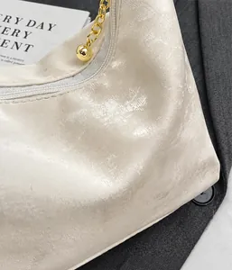 Detail of off-white pleated shoulder bag with textured fabric and gold chain strap