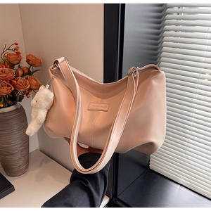 Detail view of apricot PU dumpling bag with zipper closure and white plush bear charm